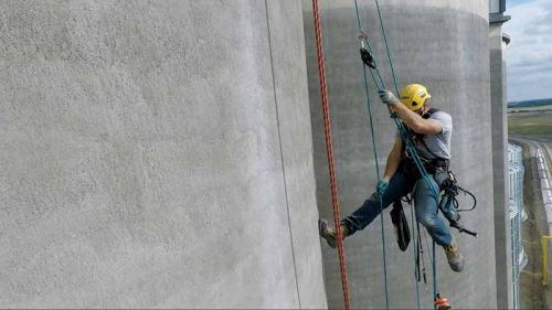 Rope access technician using a hauling system to lift aluminum composite panels (ACP) up a 36.5-m (120-ft) grain elevator.