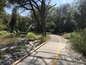 A walking trail with trees and a water body. 