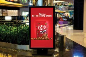 A DOOH display in a mall, featuring a KitKat ad.