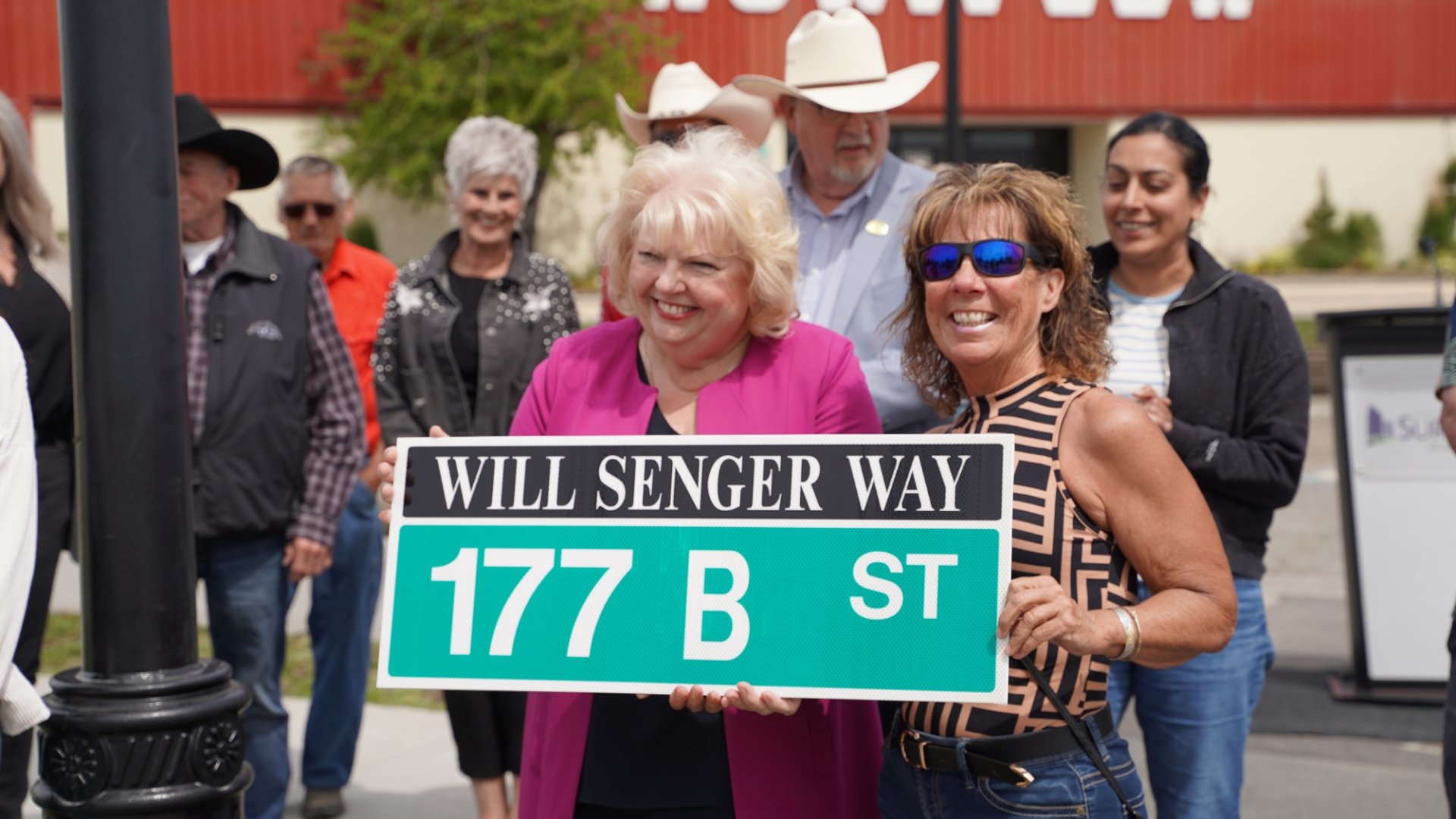 Mayor Brenda Locke stands holding the new street sign. 